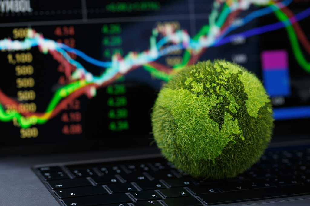 Fuzzy green earth ball on laptop keyboard with data and data visualization on screen in background